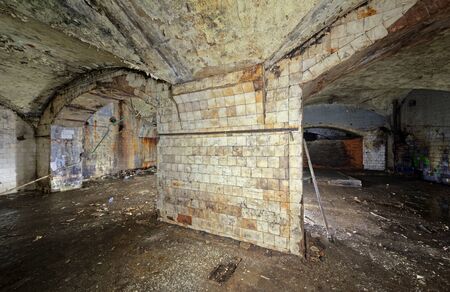 A wide column of an abandoned building lined with white tiles covered with dirt, cracks and smudges.の写真素材