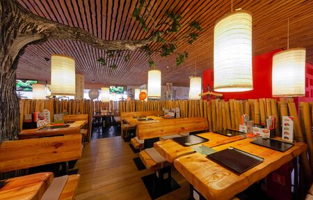 MOSCOW - SEPTEMBER 2014:: Interior of the Japanese sushi restaurant chain "TANUKI". Wooden tables and benchesのeditorial素材