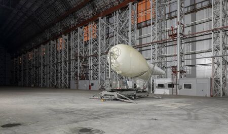 Small blimp on a mooring platform inside empty big airship hangarの写真素材