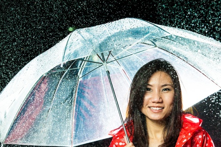 Asian women under the rain with rain coat and umbrellaの写真素材