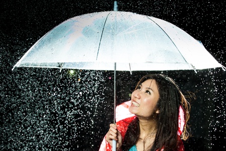 Asian women under the rain with rain coat and umbrellaの写真素材