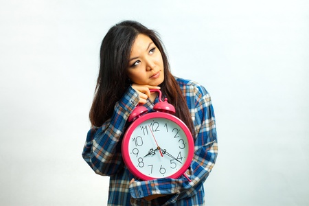 Asian woman holding an alarm clock in the  morningの写真素材