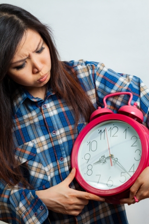 Asian woman holding an alarm clock in the  morningの写真素材