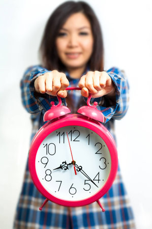 Asian woman holding an alarm clock in the  morningの写真素材