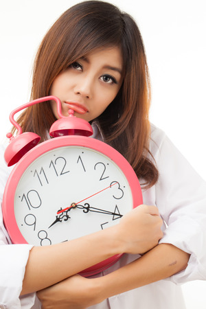 Asian woman holding an alarm clock in the  morningの写真素材