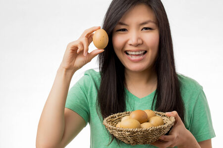 asian woman holding eggs shooting in white backgroundの写真素材