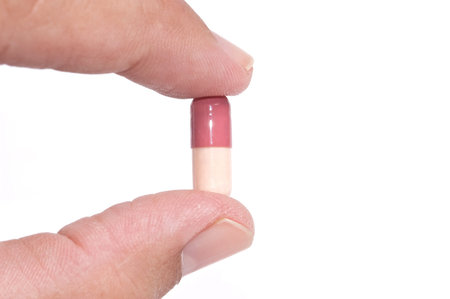 hand with capsule isolated on white