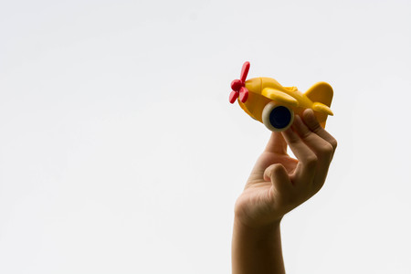 child hand holding plastic toy planeの写真素材