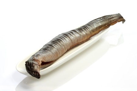 Whole smoked eel with garnish on a plateの写真素材