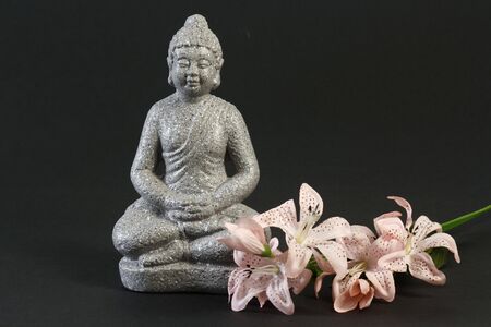 Buddha sculpture in lotus position over black backgroundの写真素材