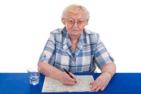 Elderly woman solving a crossword puzzle - isolatedの写真素材