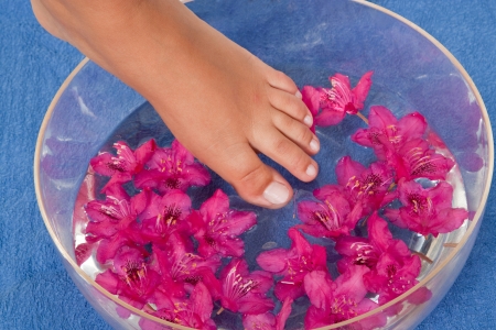 Feet in a bowl of water with pink blossomsの写真素材