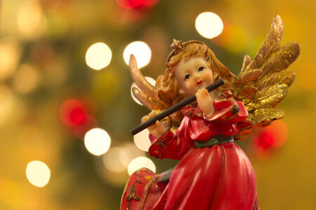 Angel figurine with flute over bokeh background on christmasの写真素材