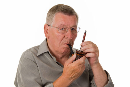 Old man tamping a pipe - isolated
