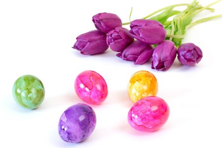 Painted easter eggs with purple tulips over white backgroundの写真素材