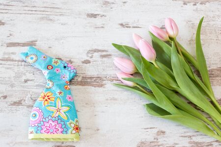 pink tulips with egg cozy on bright rustic wooden background