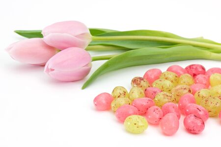 Jelly Easter eggs near pink tulips on white background