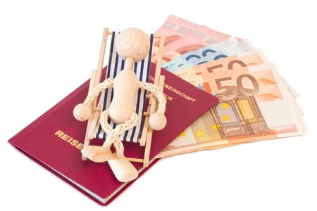Wooden puppet on a mini deck chair with passport and moneyの写真素材