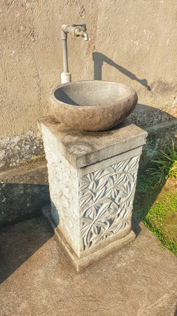 A charming stone sink, a testament to rustic simplicity, stands gracefully beside a sturdy cement wall, adding character to any spaceの写真素材