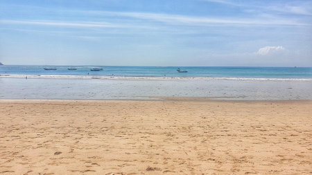A tranquil beach on Bali's Nusa Penida island, marked with solitary footprints in the sand and a distant boat, capturing the essence of serene seclusionの写真素材