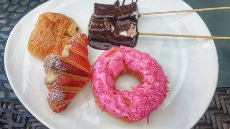 Indulge in a delectable assortment of donuts and pastries beautifully arranged on a white plate, a mouthwatering treat for any occasionの写真素材