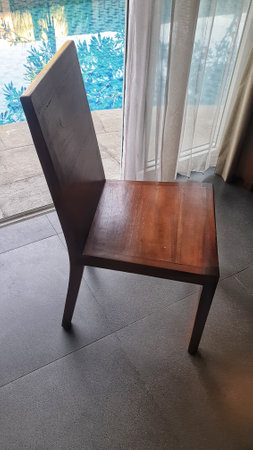 A warm, inviting scene with a wooden chair bathed in sunlight, positioned perfectly by a window, offering a serene spot to relax and unwindの写真素材