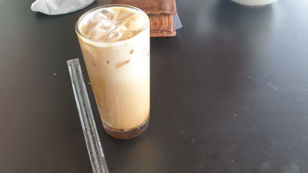 Indulge in the sheer pleasure of a chilled glass of iced coffee, complete with a handy straw. A delightful caffeine fix awaitsの写真素材