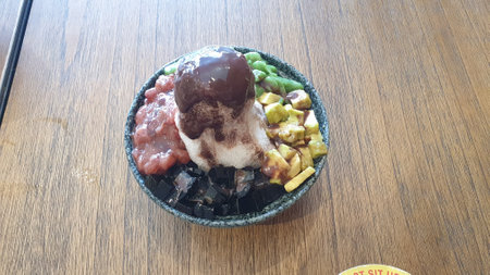 Indulge in the vibrant world of a mixed fruit ice dessert presented on a rustic wooden table, a refreshing treat for your sensesの写真素材