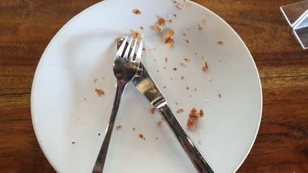 A white plate adorned with a sleek fork and knife, setting the scene for a sophisticated dining experience. Perfect for culinary or restaurant projectsの写真素材
