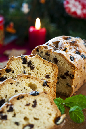 Sliced christmas fruitcake with raisins and mint leaf on christmas background の写真素材