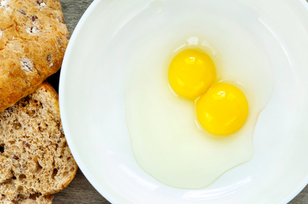 Quail eggs yellow yolk in white porcelain bowl with bread  Indoors closeup 