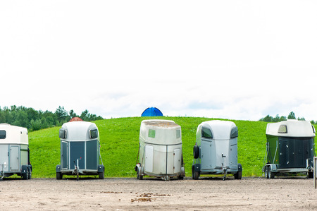 Many horse trailers in the green park. Outdoors.