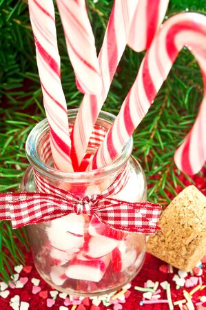 Bunch of red and white striped candy canes in glass jar on christmas background. Close up indoors vertical image.の写真素材