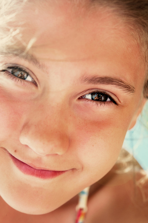 Low angle view of beautiful  smiling playful girl closeup portrait. Vibrant summertime vertical image.の写真素材