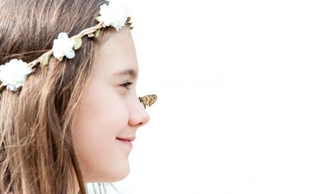 Portrait of boho style cheerful girl with floral headband on head and butterfly on nose. Summertime horizontal  outdoors image with copy spaceの写真素材