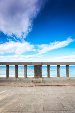 Stone quayside at mediterranean sea coast. Sicily, Italy. Multicolored outdoors toned vertical image on a blue sky background.の写真素材