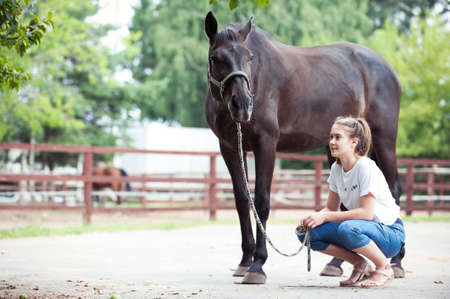 Young lady close to her favorite dark chestnut horse. Colored outdoors horizontal  image with filterの写真素材