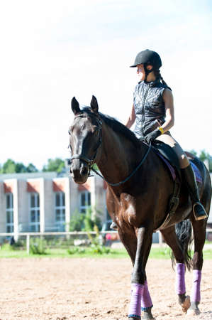 Teenage girl equestrian riding horseback at riding school place. Kleisti, latvia, Riga. Vibrant colored summertime outdoors vertical image.の写真素材