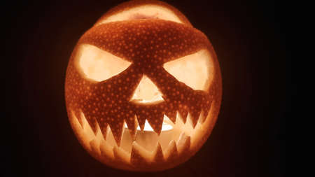 Handmade halloween pumpkin scary smile for party night on dark background. Closeup portrait. Mobile phone horizontal image with copy space.の写真素材