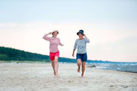 Two young women have fun together on stormy seaside. Friends/sisters. Summertime outdoors inspirational horizontal image. Spectacular cloudy sky backgroundの写真素材