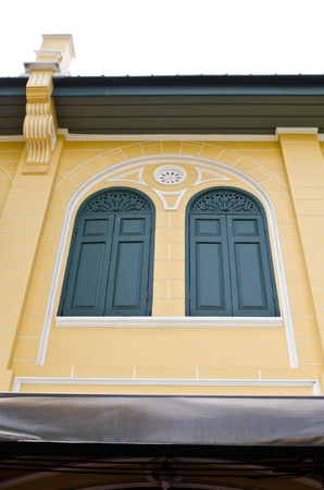 Green classic windows with yellow wall taken from an old house row in Ratanakosin Island, Bangkokの写真素材