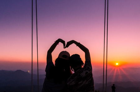 silhoutte of two people making a heart shape with twilightの写真素材