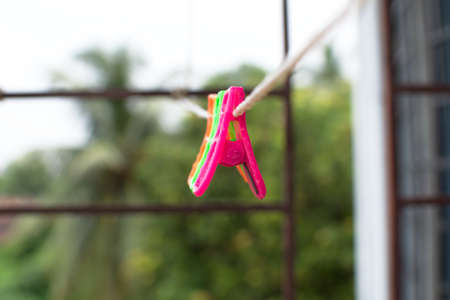 A trio of colourful plastic clothes pegs hanging on a washing line with blurred background