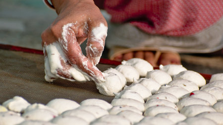 A bengali woman is making biuli dal bori on iron net surface. Bori is a form of dried lentil dumplings popular in Bengali cuisine. It is made from a paste of urad dal and winter melon.の写真素材