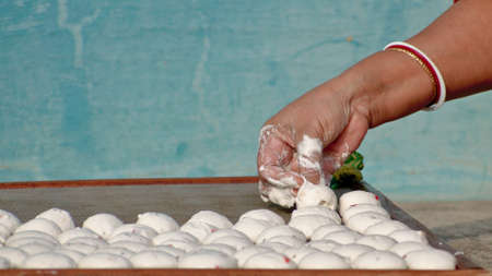 A bengali woman is making biuli dal bori on iron net surface. Bori is a form of dried lentil dumplings popular in Bengali cuisine. It is made from a paste of urad dal and winter melon.の写真素材