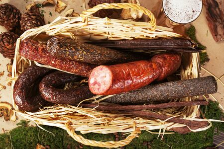 Variety of sausage products in the basket on the wooden table.の写真素材