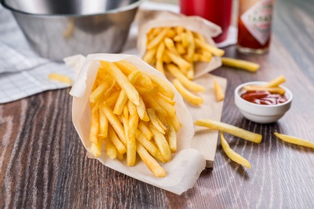 Fresh fried french fries with ketchup on wooden background