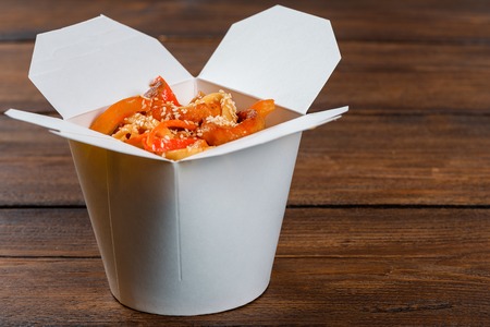Noodles in a white box on a wooden background close up shotの写真素材