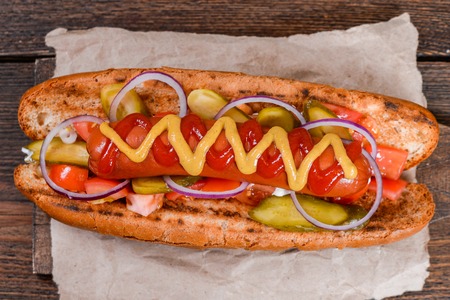 Grilled hot dogs with mustard, ketchup and relish on a picnic tableの写真素材
