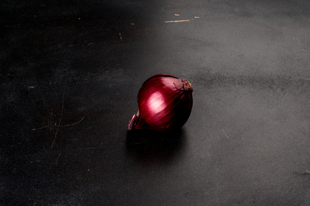 A red onion isolated against a black background. Shot from the sideの写真素材